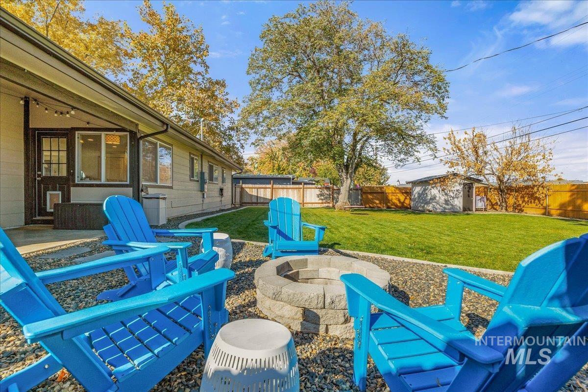 Fenced backyard featuring a patio, an outdoor fire pit, a ceiling fan, and a storage shed