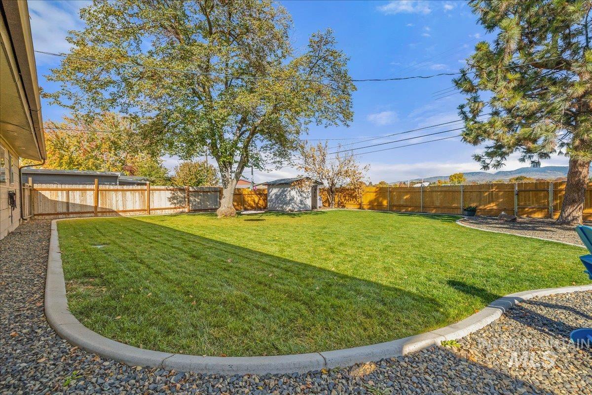 Fenced backyard featuring a storage unit