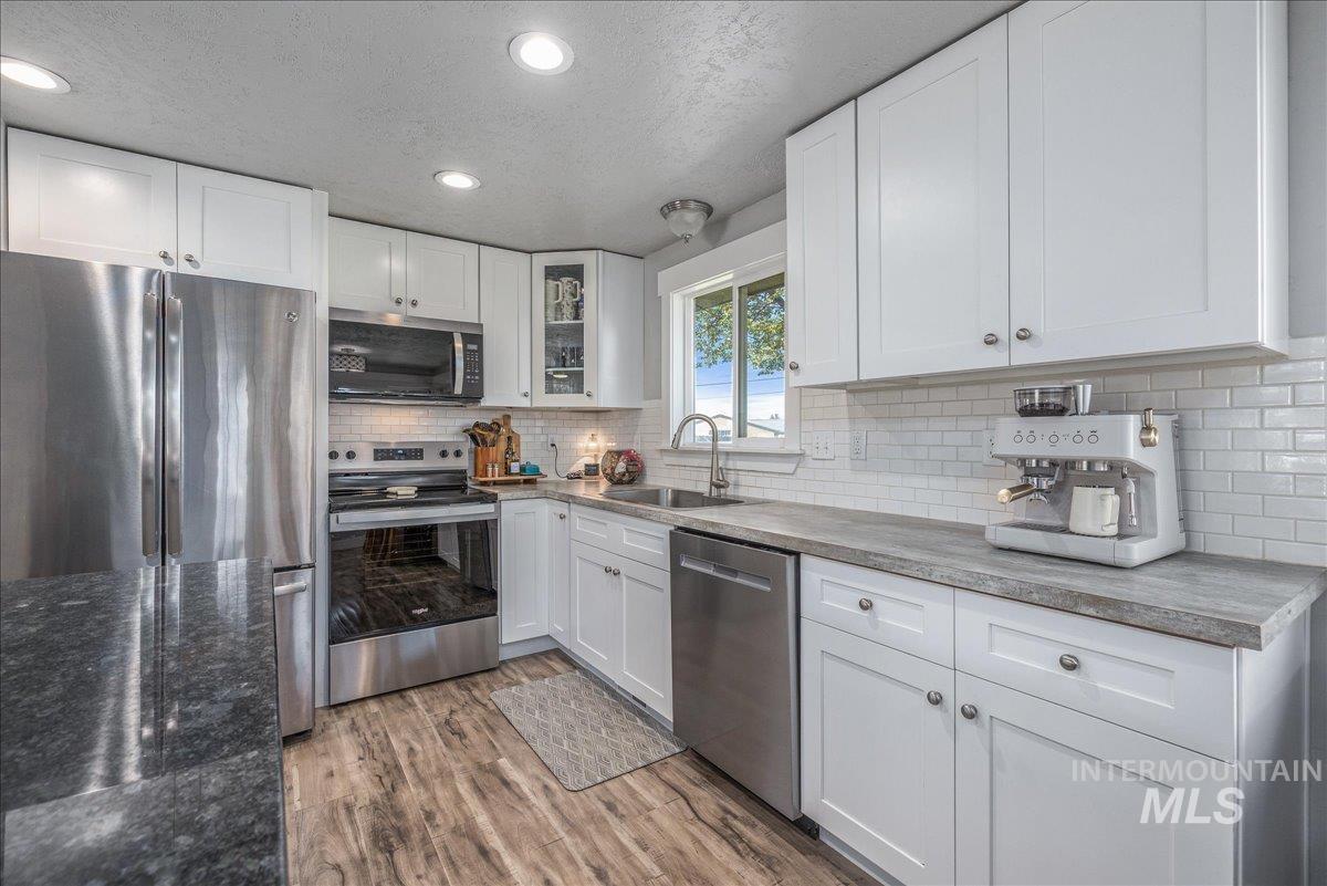 Kitchen featuring appliances with stainless steel finishes, a textured ceiling, white cabinetry, recessed lighting, and light wood-style floors