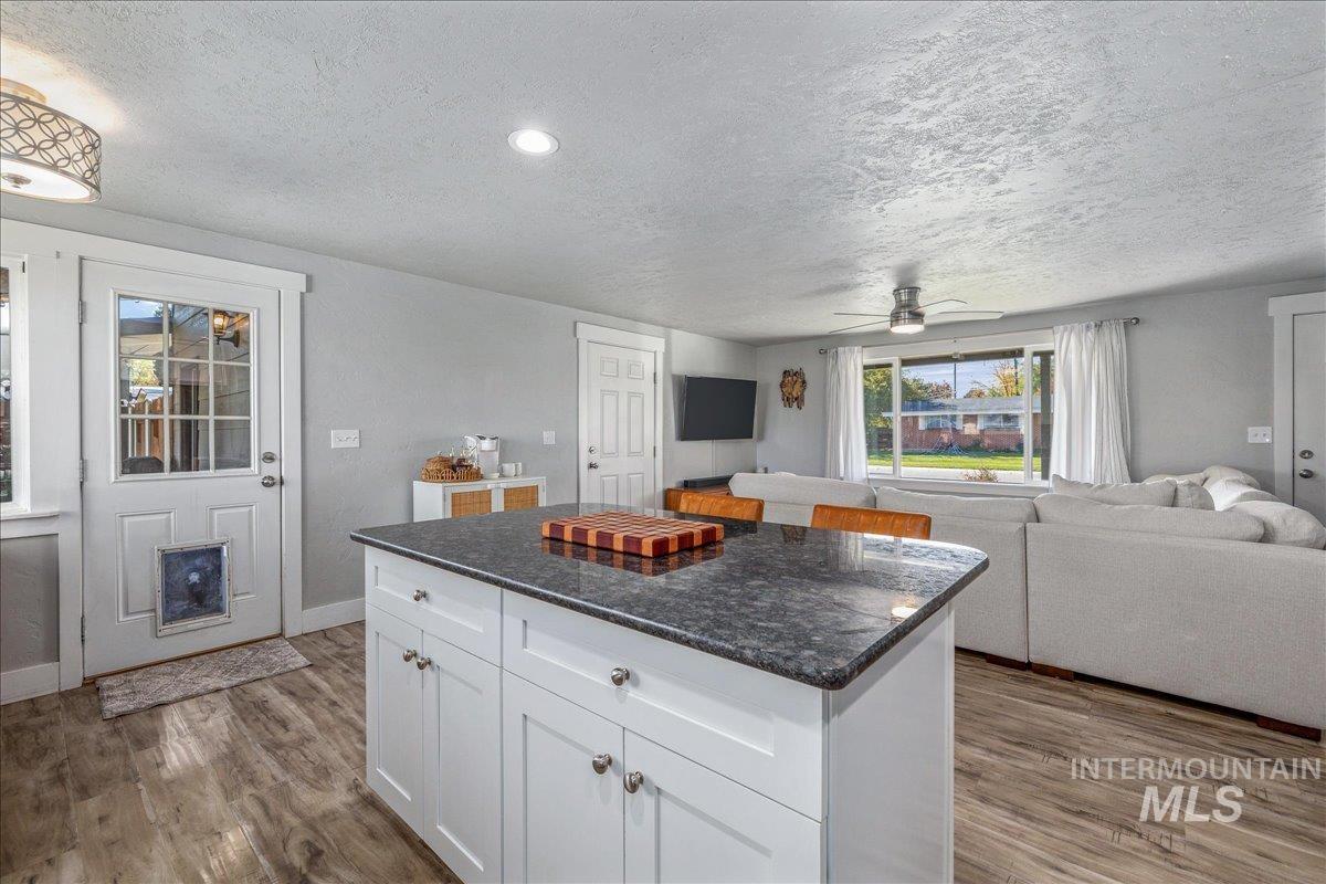 Kitchen with white cabinets, open floor plan, light wood-style floors, a center island, and a textured ceiling