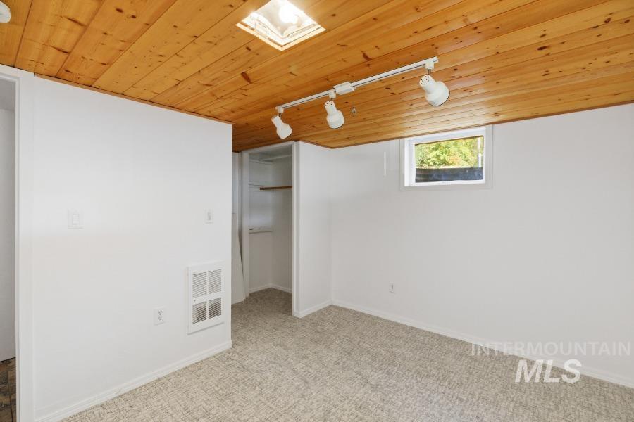 Unfurnished bedroom with wood ceiling, track lighting, carpet, and a closet