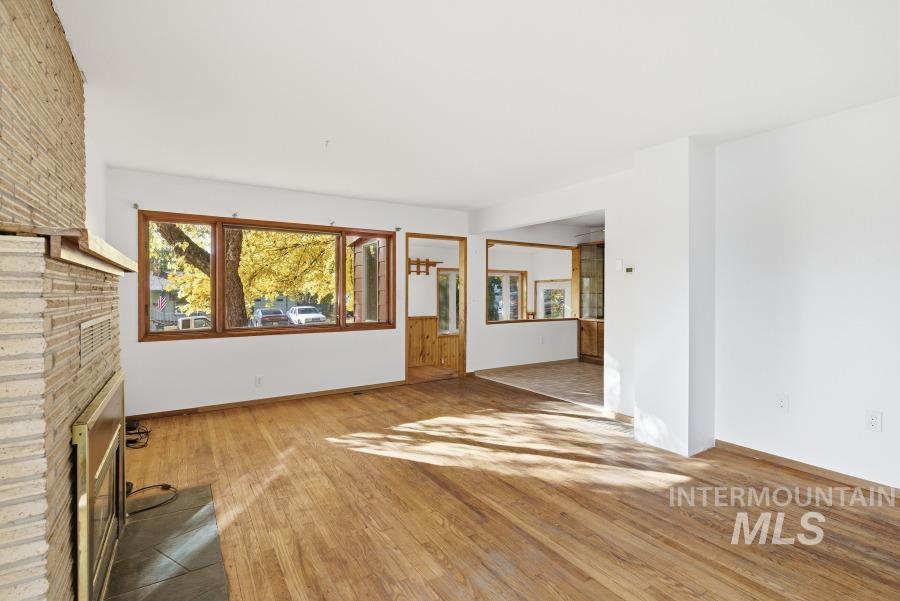 Unfurnished living room with a brick fireplace and light wood-style floors