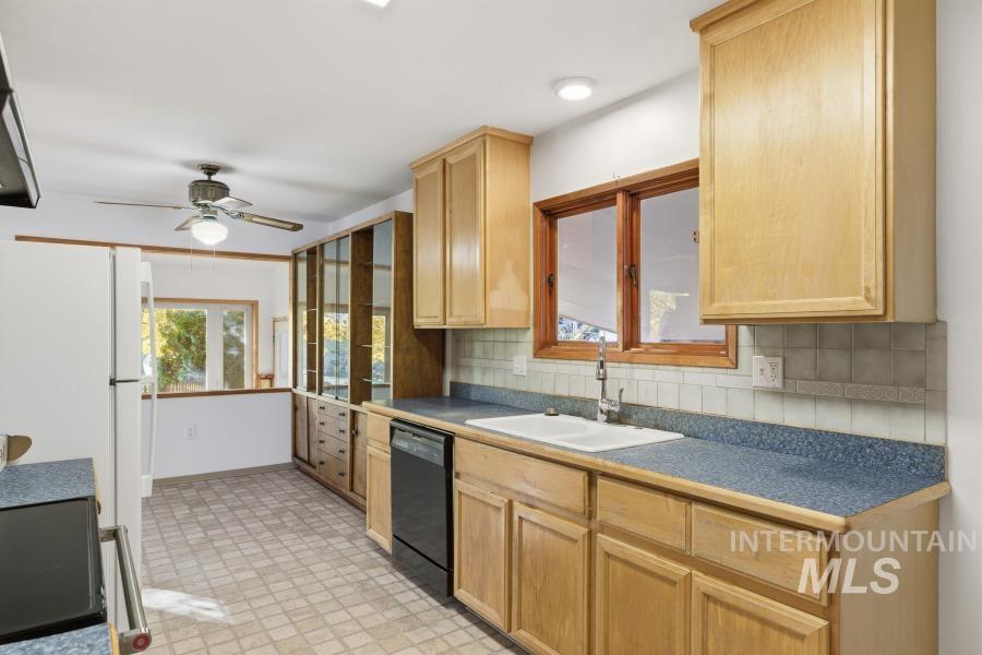Kitchen featuring light brown cabinetry, decorative backsplash, range, black dishwasher, and ceiling fan