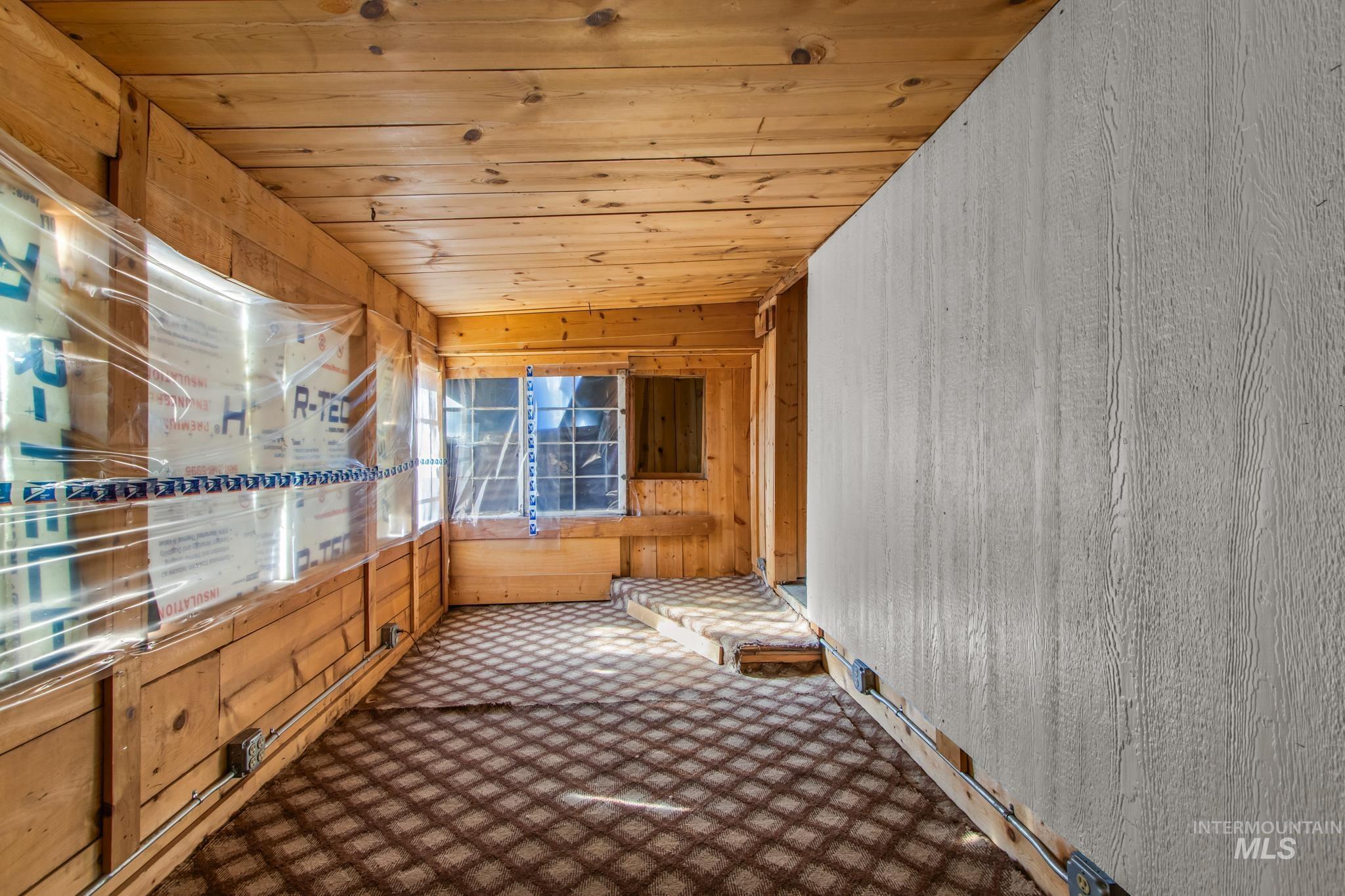 Empty room featuring wooden walls, wooden ceiling, and carpet floors