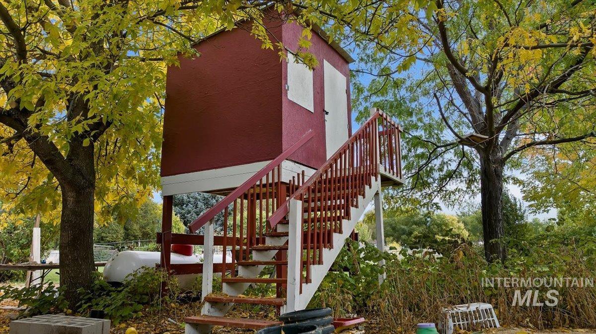View of side of home featuring stairway, stucco siding, a deck, and view of scattered trees