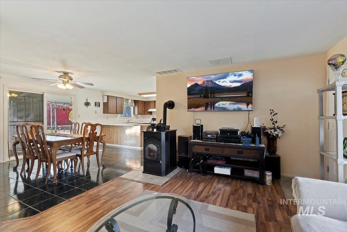 Living area featuring a wood stove, wood finished floors, and ceiling fan