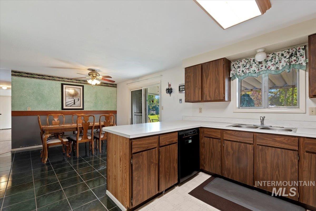 Kitchen with a peninsula, light countertops, black dishwasher, and plenty of natural light