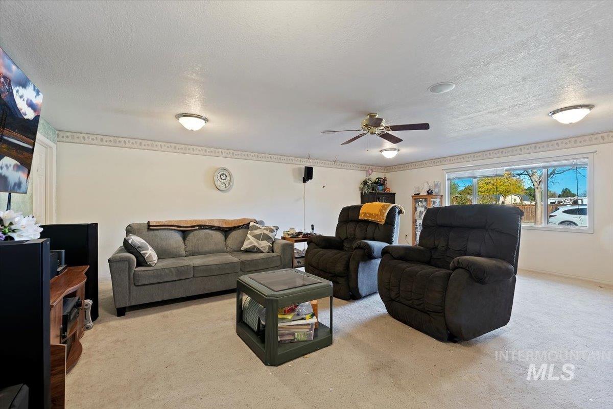Living area featuring carpet floors, a textured ceiling, and a ceiling fan