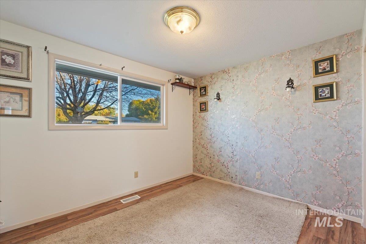 Spare room with wallpapered walls and wood finished floors