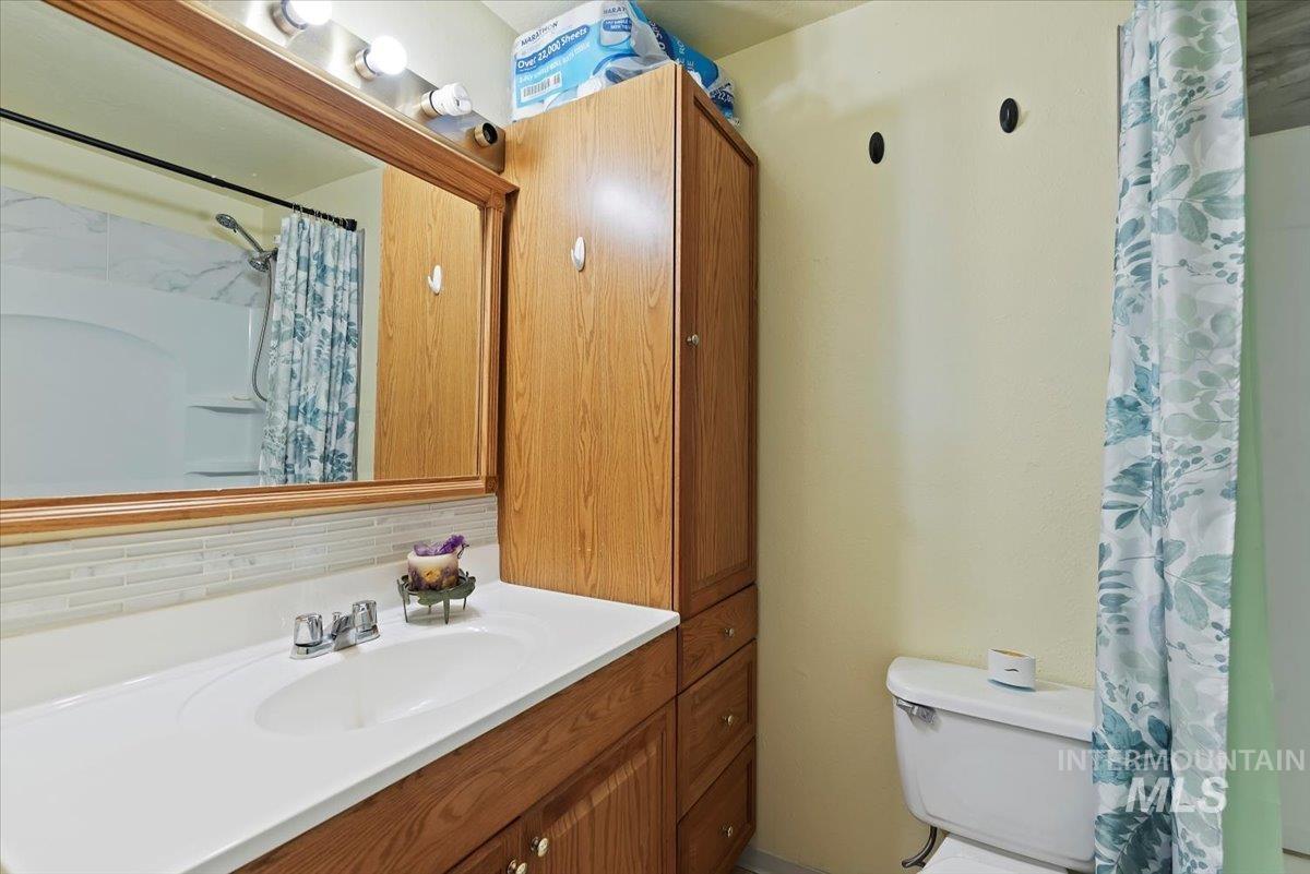 Full bath with vanity, a shower with shower curtain, and tasteful backsplash