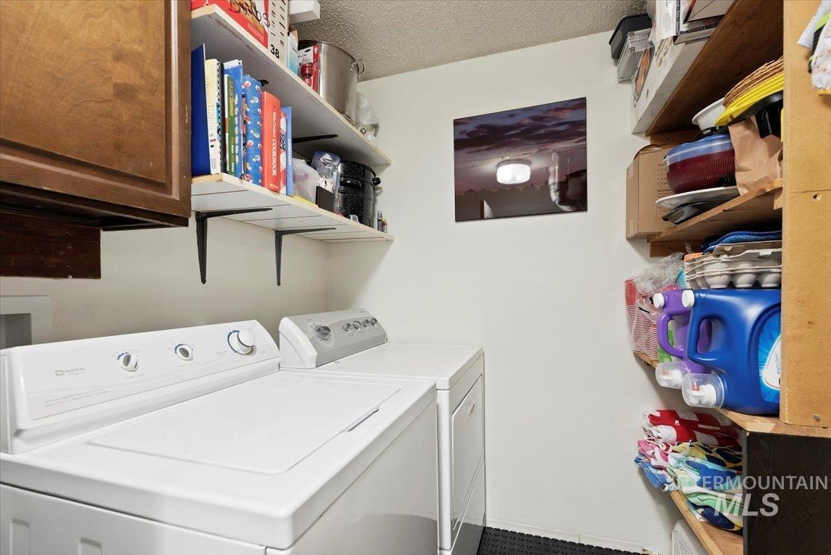Laundry area with independent washer and dryer, a textured ceiling, and cabinet space