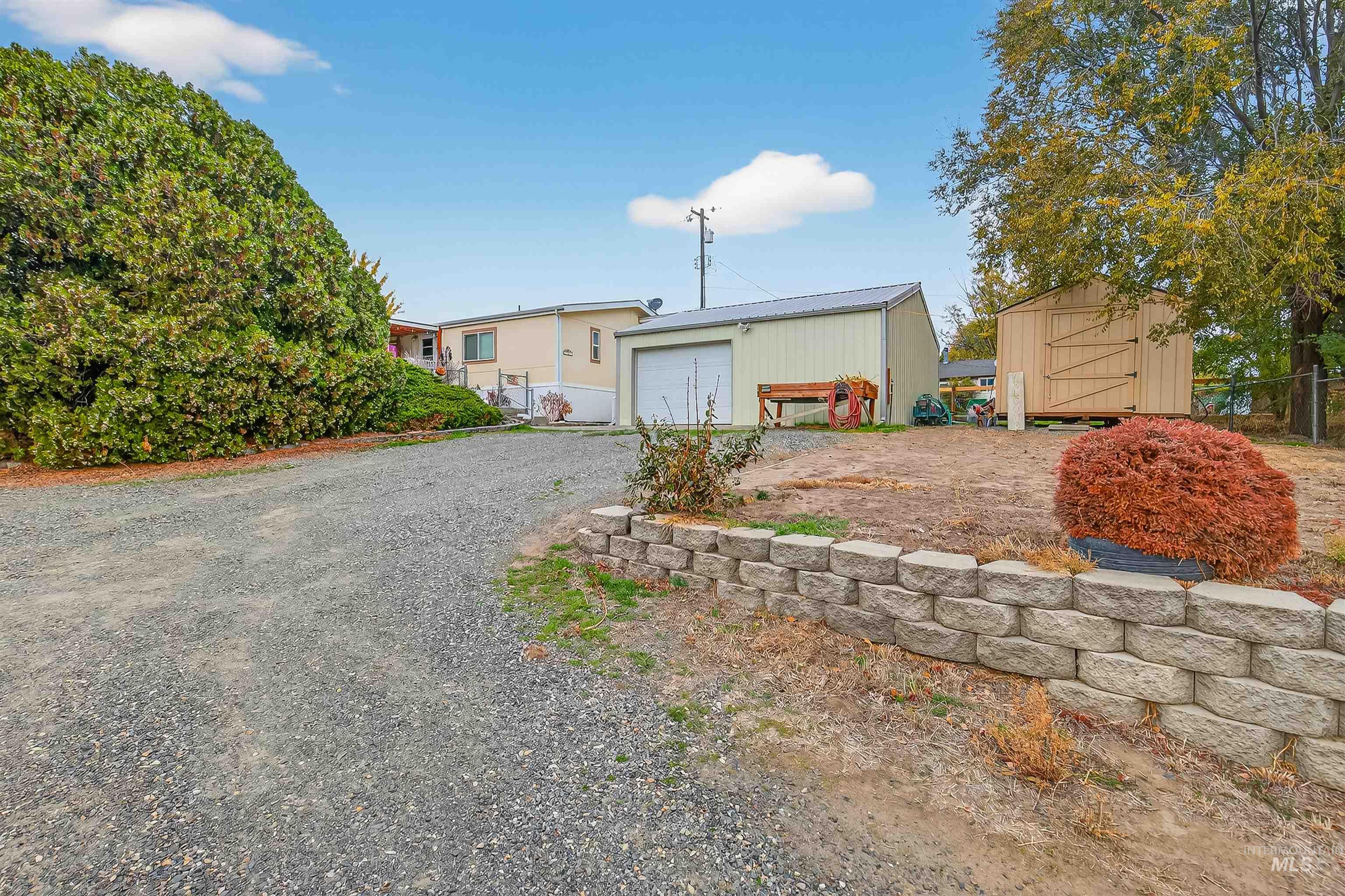 View of front of home featuring driveway and a storage shed