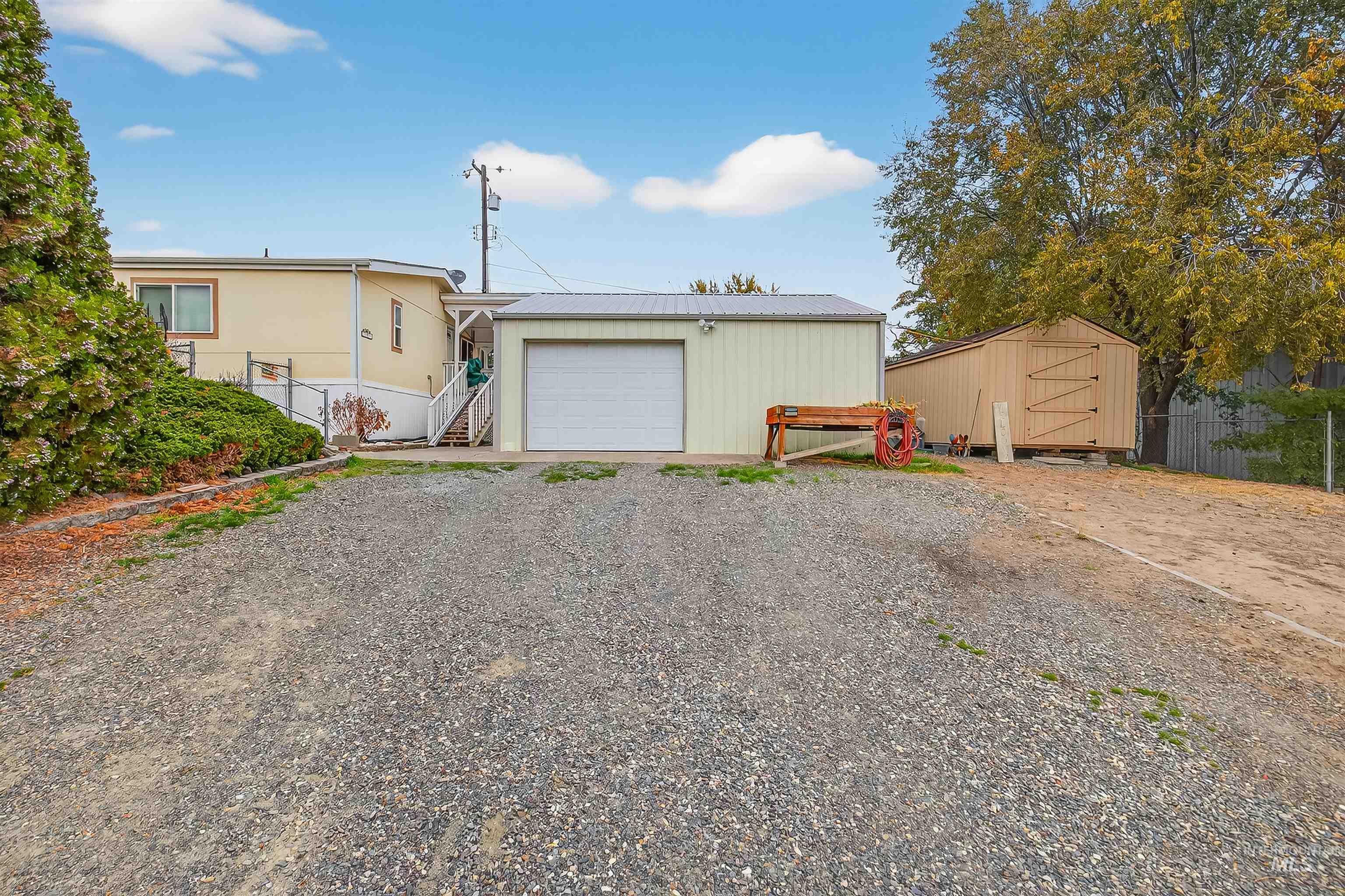 View of front of house with driveway, a garage, and a storage unit