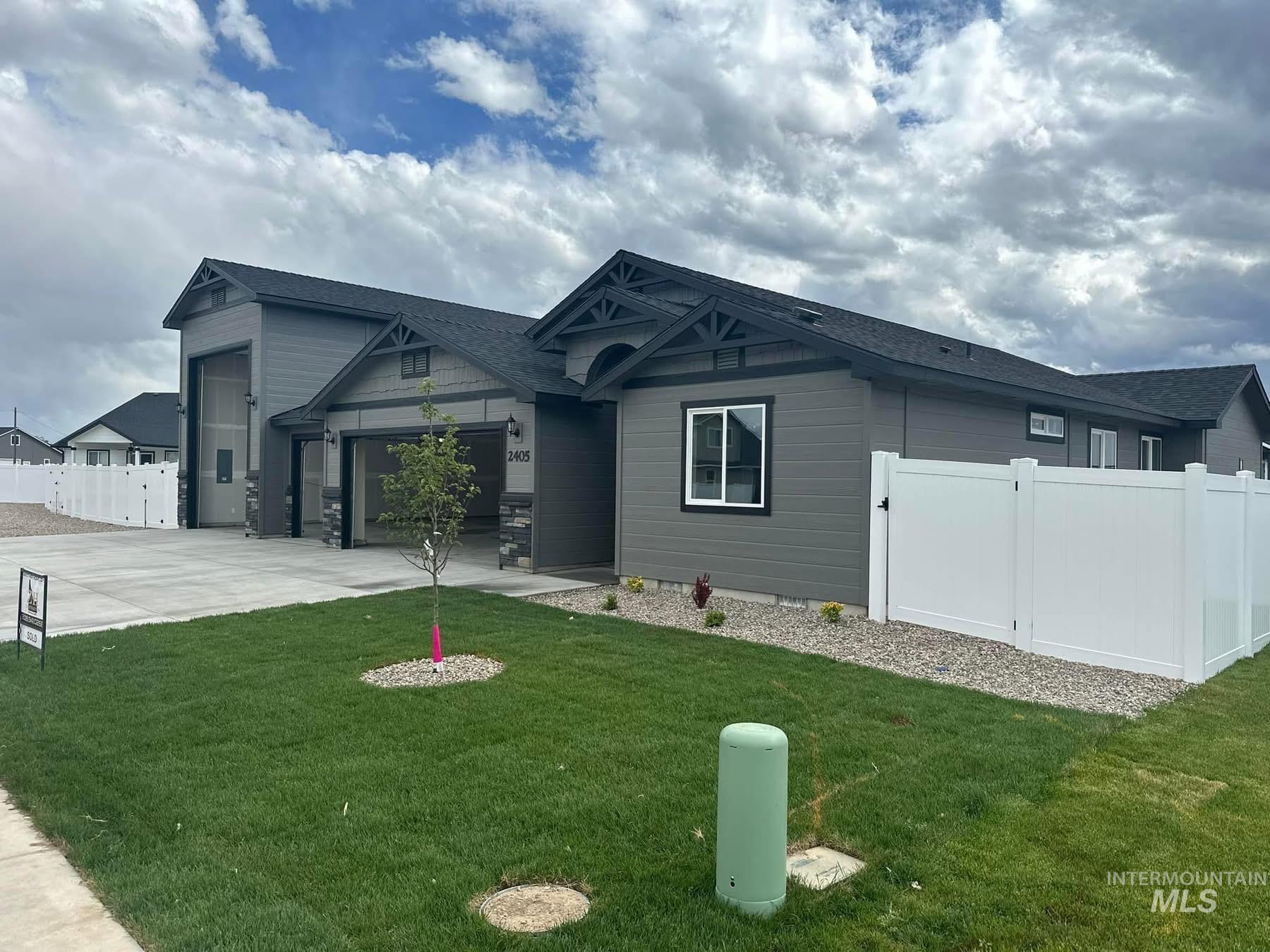 View of front of property featuring a gate, an attached garage, driveway, and a shingled roof