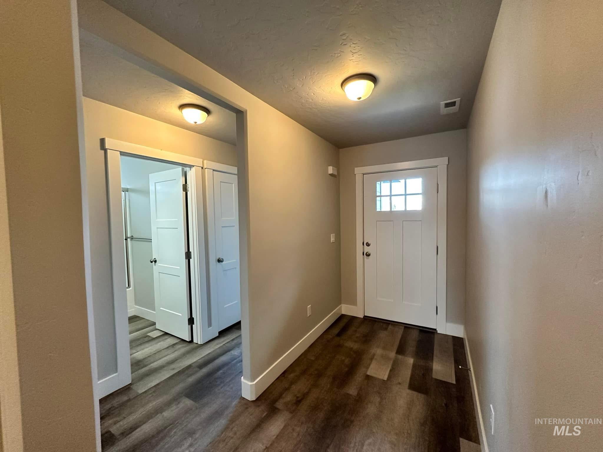 Doorway to outside with a textured ceiling and wood finished floors