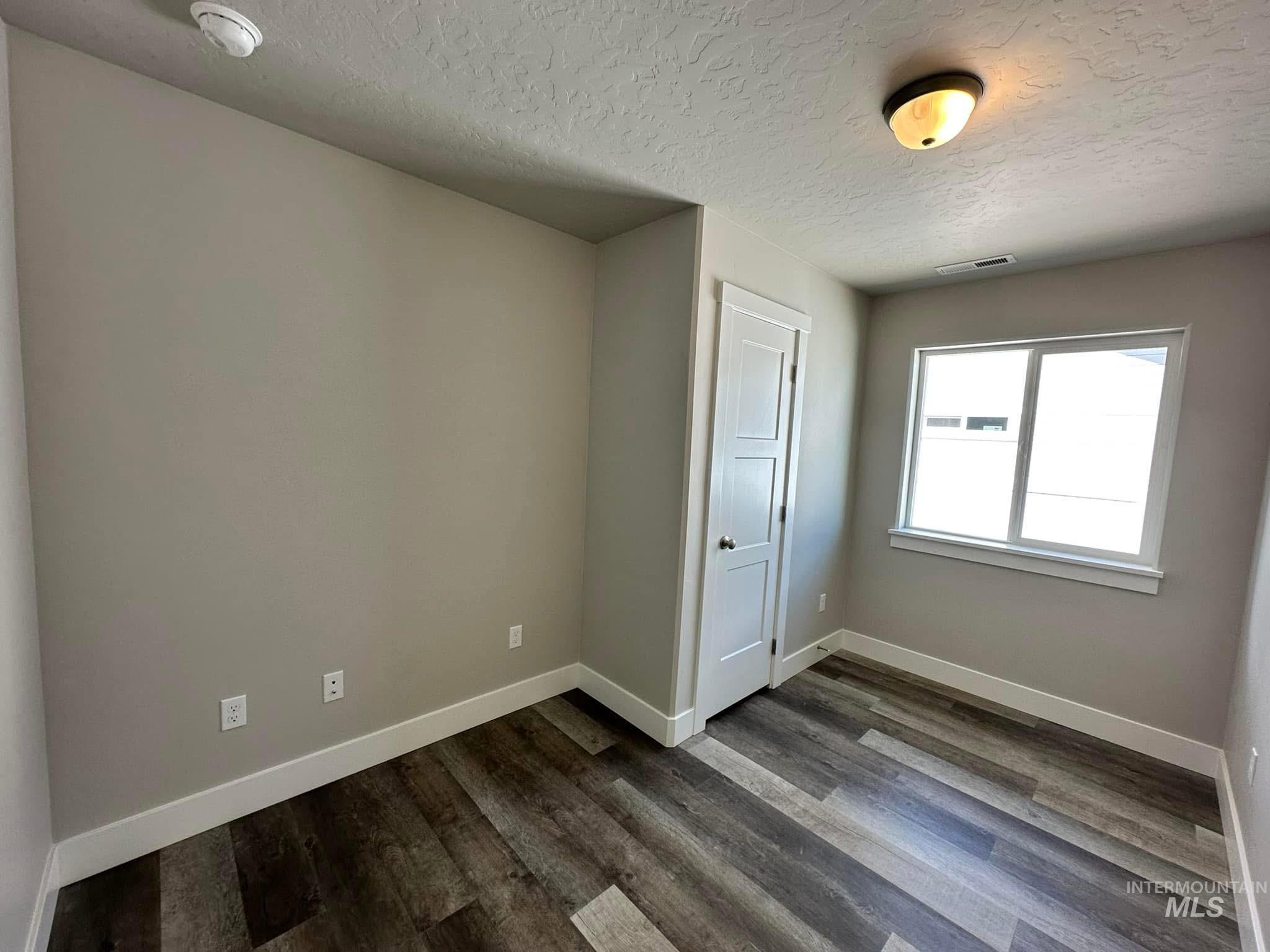 Unfurnished bedroom featuring a textured ceiling and dark wood-style flooring
