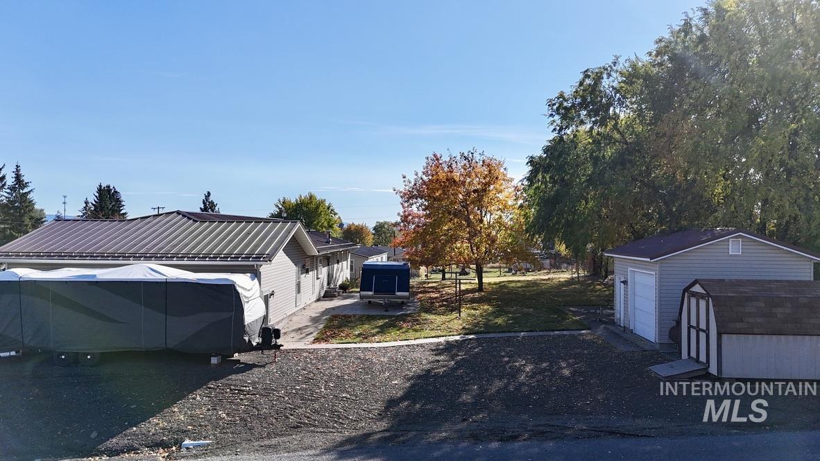 View of side of home with a storage unit, a metal roof, a garage, and a patio area