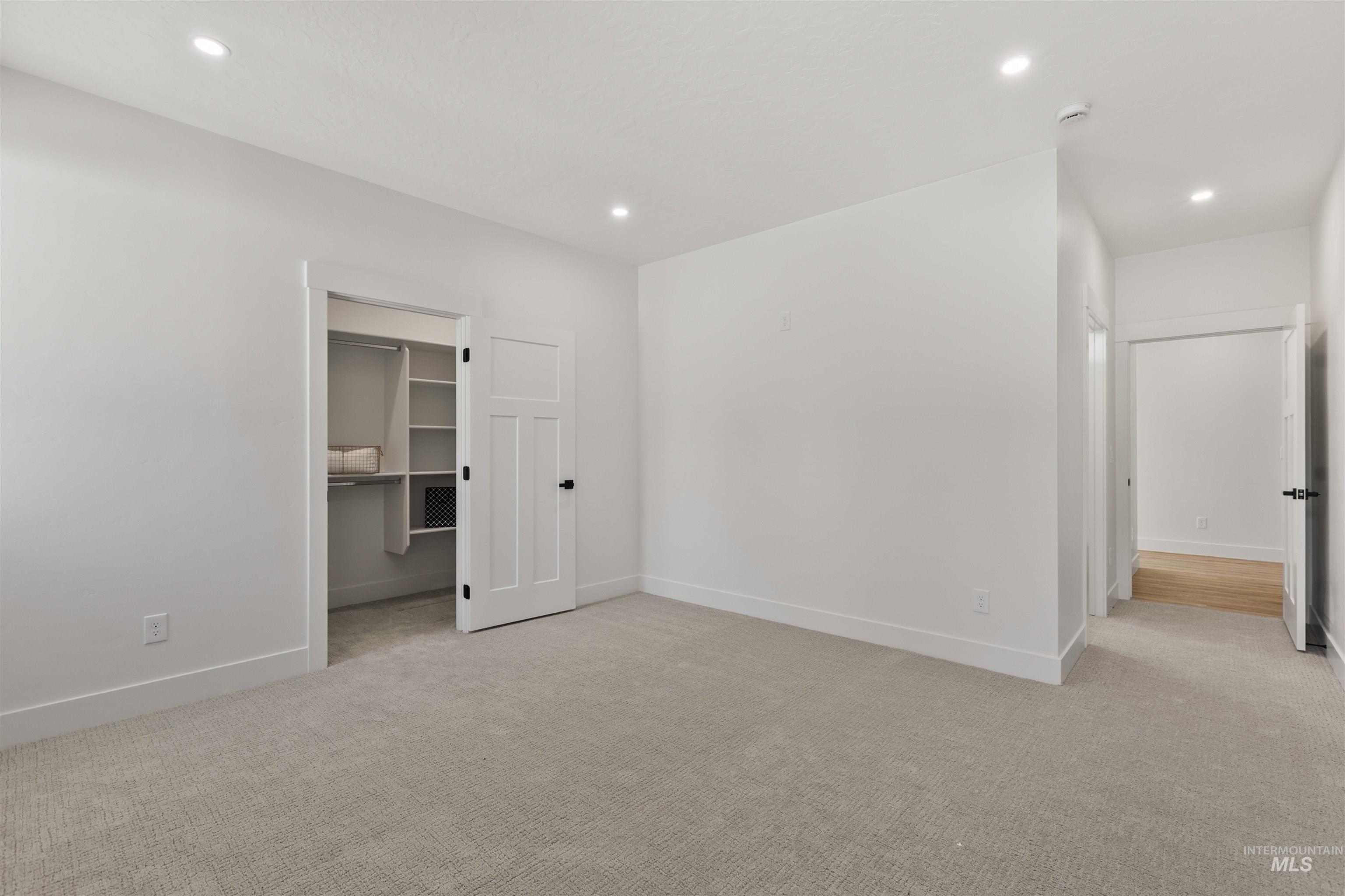 Unfurnished bedroom with a spacious closet, light carpet, and recessed lighting