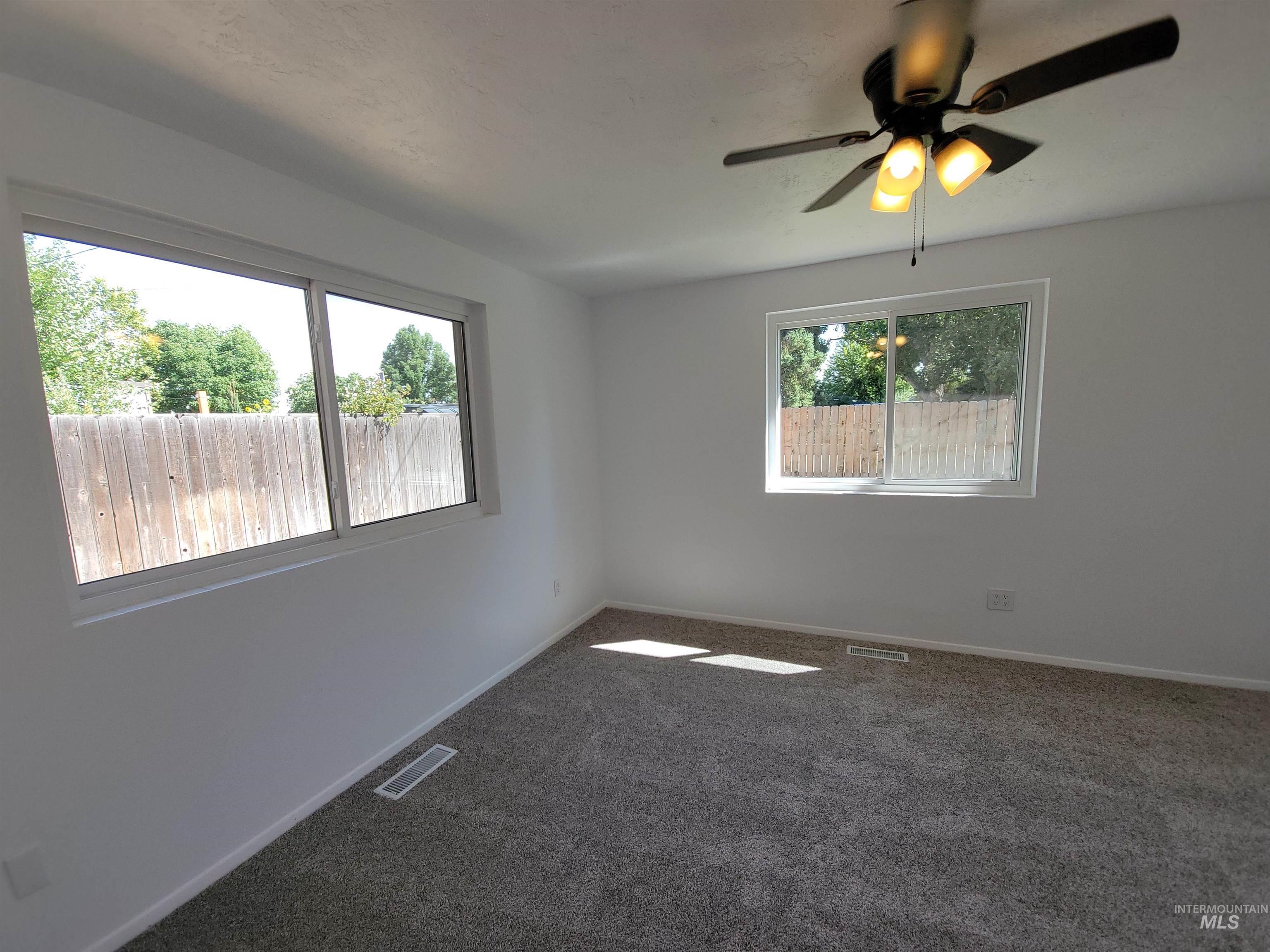 Spare room featuring dark colored carpet and ceiling fan