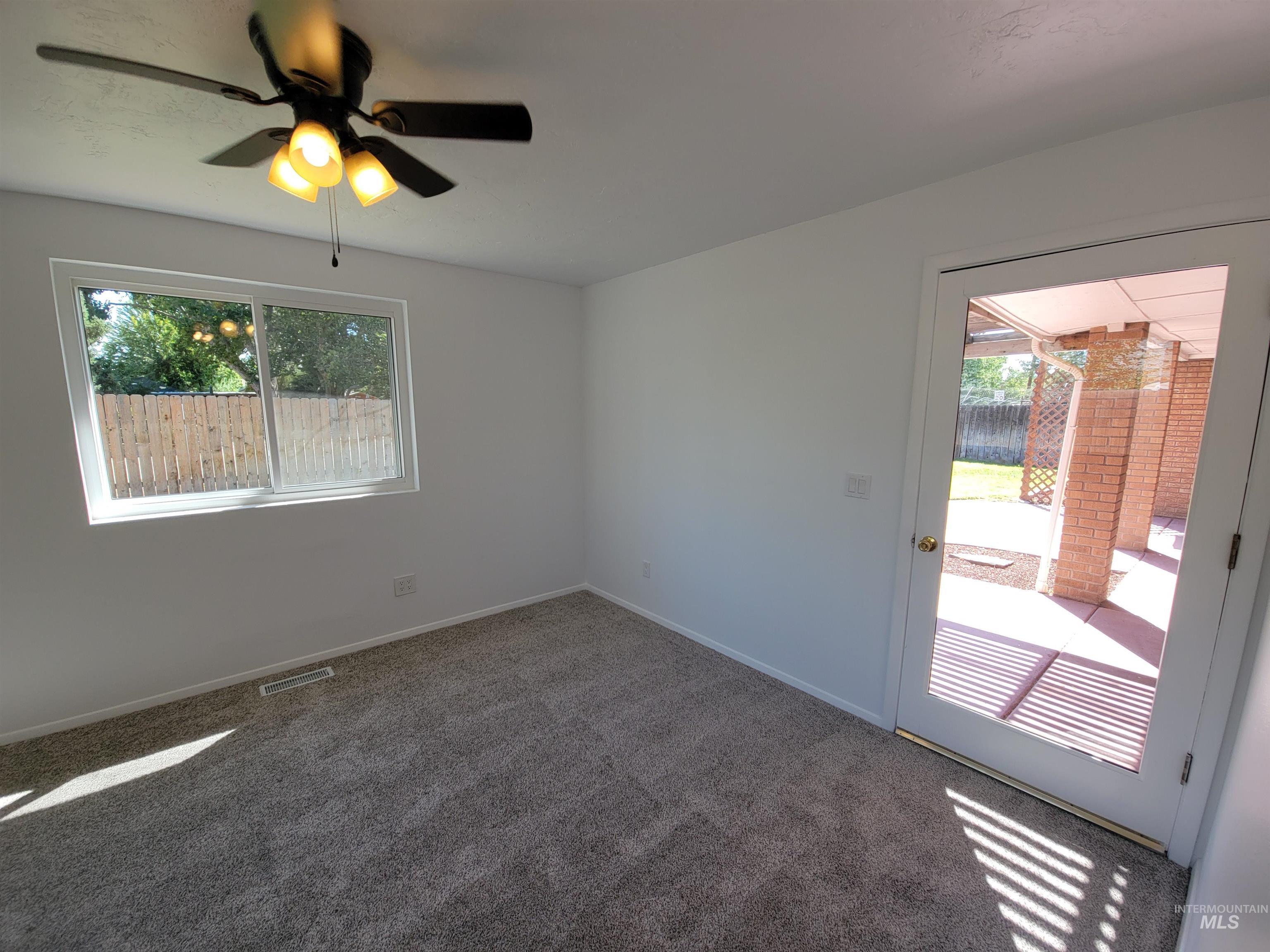 Carpeted empty room featuring a ceiling fan and baseboards
