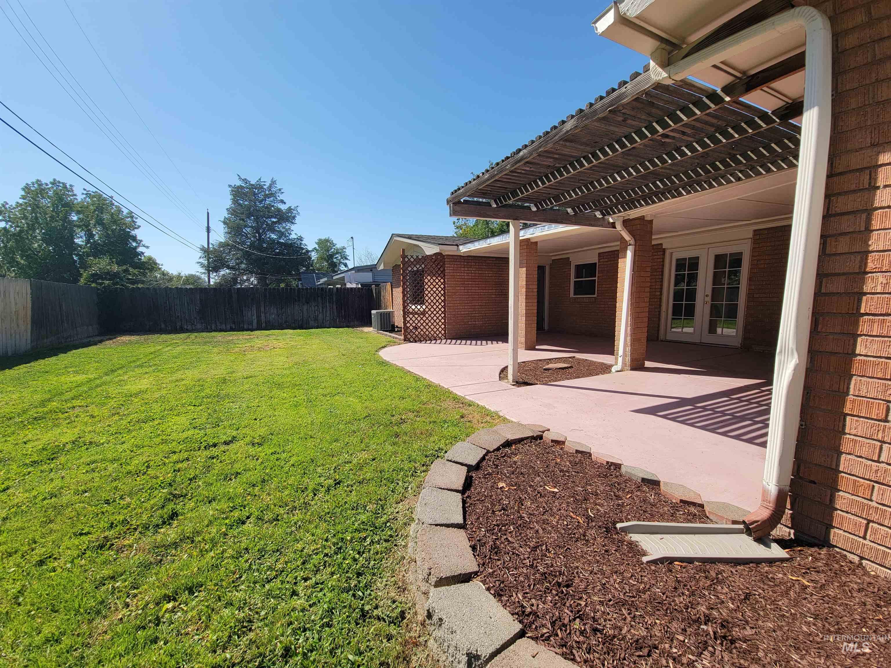 Fenced backyard with a pergola, a patio area, and french doors