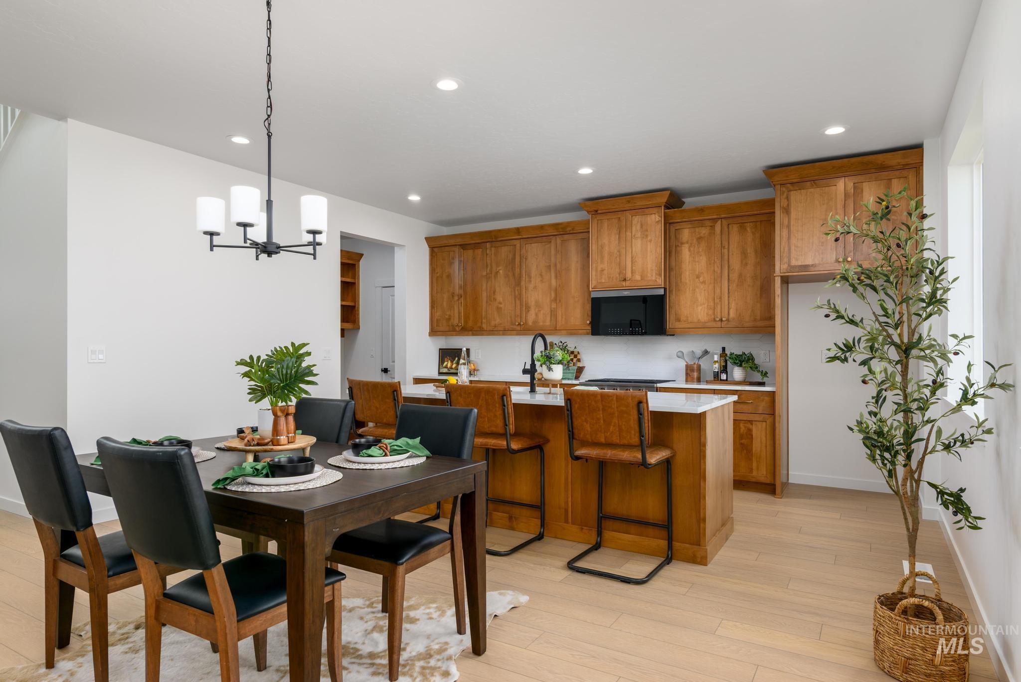 Kitchen featuring brown cabinetry, decorative light fixtures, a chandelier, recessed lighting, and light wood-style flooring