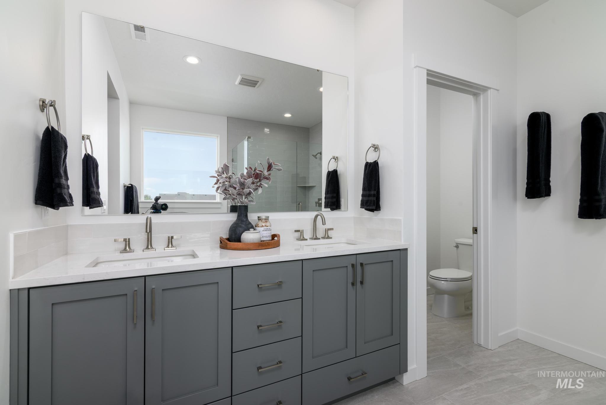 Bathroom with double vanity, a shower stall, and recessed lighting
