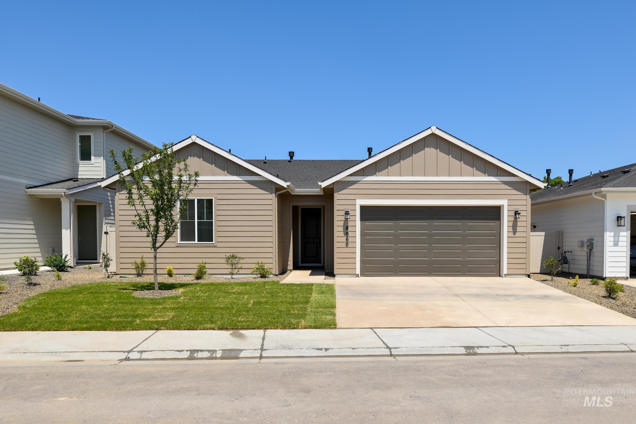 Ranch-style home with board and batten siding, concrete driveway, an attached garage, and a front lawn