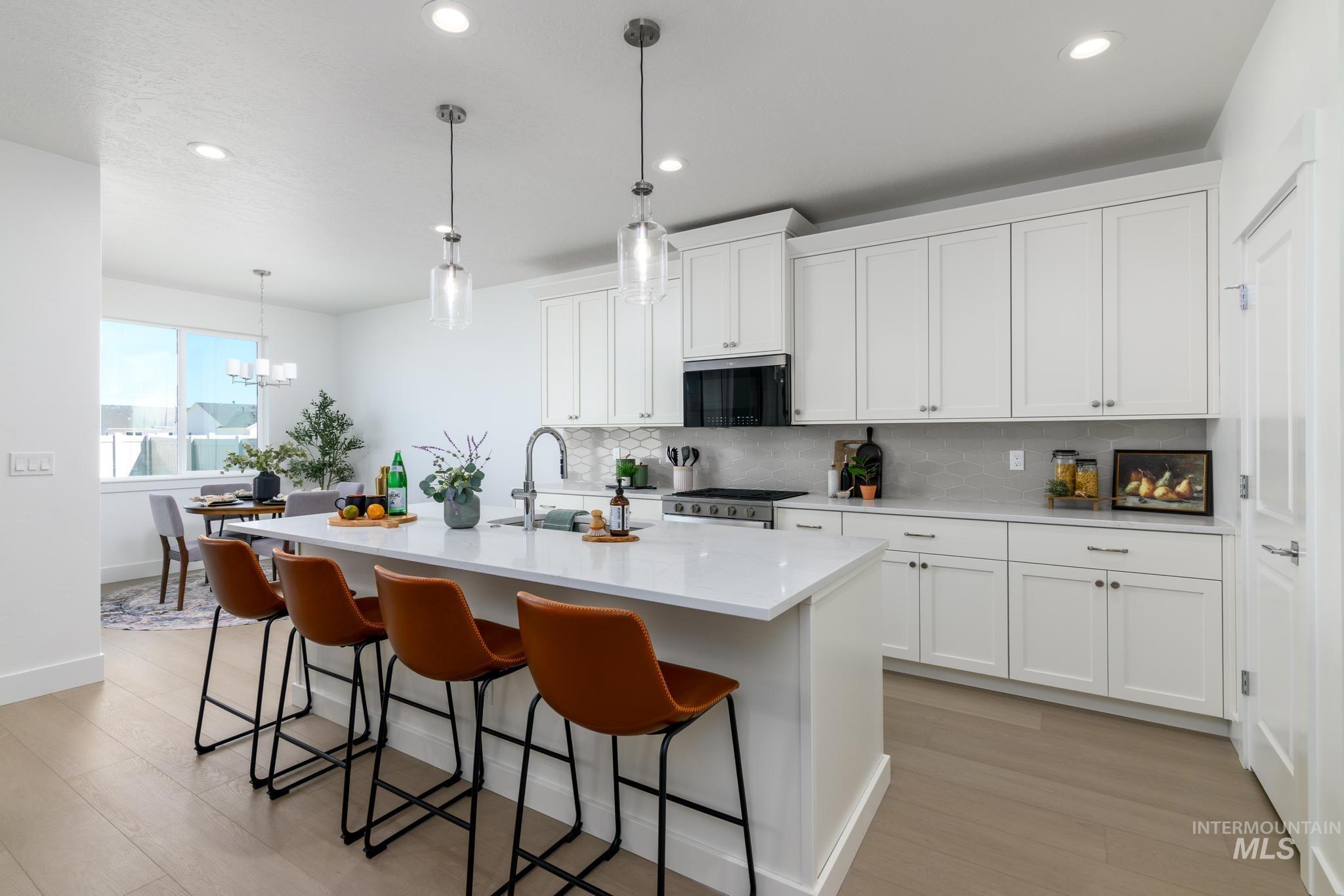 Kitchen featuring backsplash, decorative light fixtures, white cabinetry, and recessed lighting