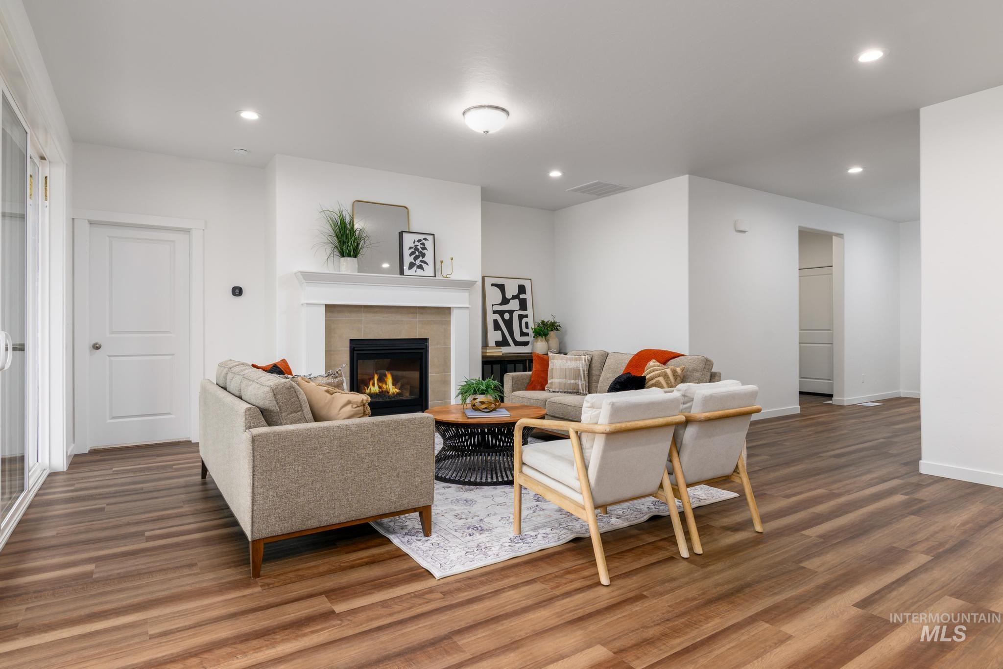 Living area featuring recessed lighting, a tiled fireplace, and wood finished floors