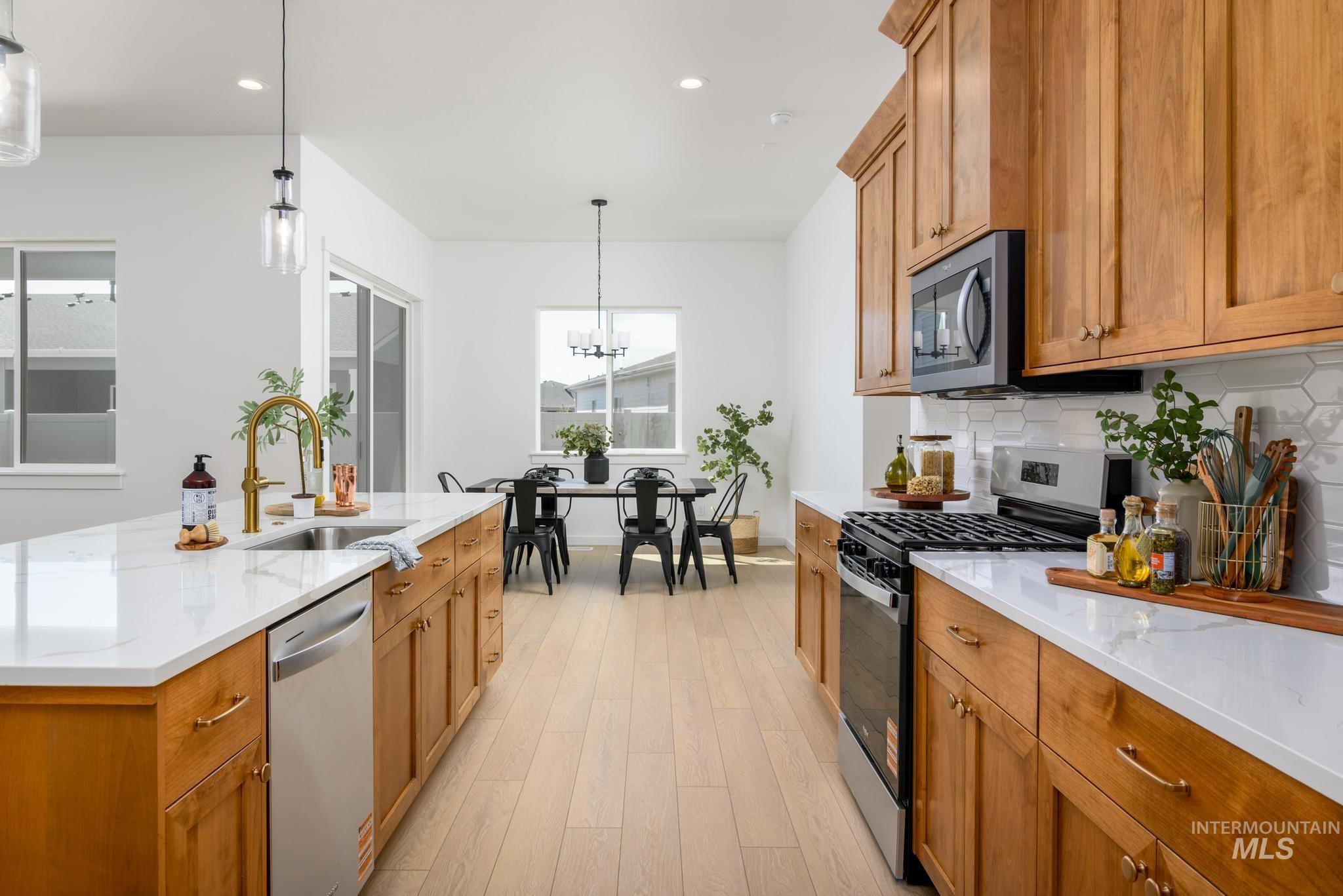 Kitchen with stainless steel appliances, decorative backsplash, pendant lighting, recessed lighting, and light stone counters