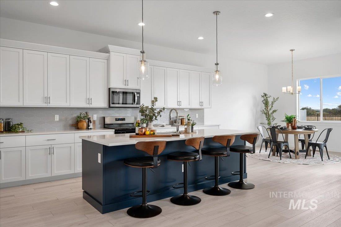 Kitchen with decorative backsplash, decorative light fixtures, white cabinetry, and recessed lighting