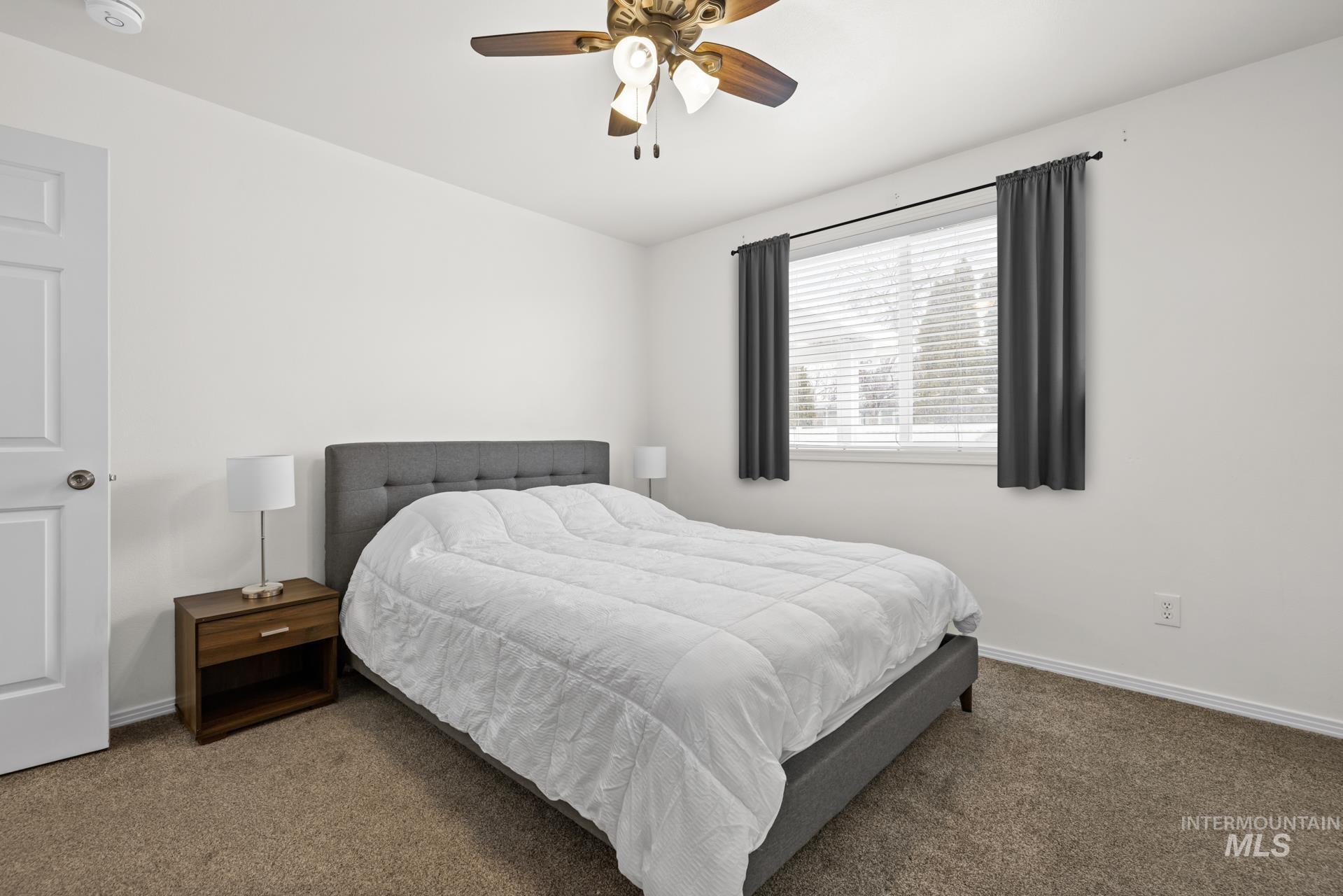 Carpeted bedroom with ceiling fan and baseboards