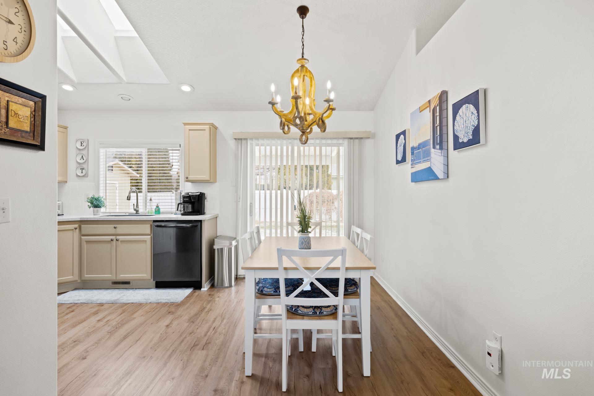 Dining room with a chandelier, light wood-style flooring, recessed lighting, and a skylight