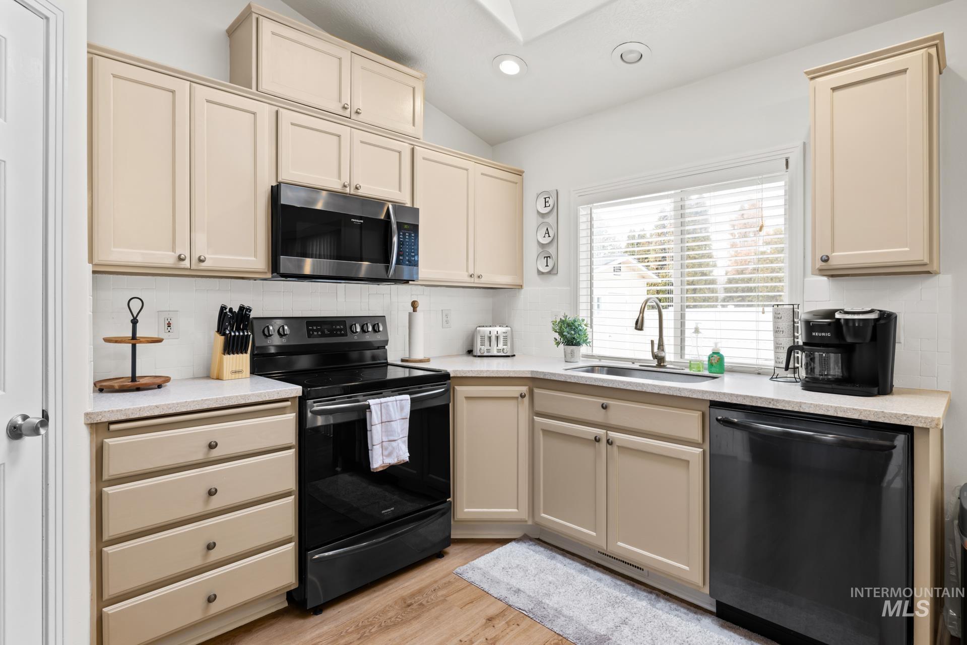 Kitchen featuring cream cabinets, black appliances, backsplash, recessed lighting, and light wood-type flooring
