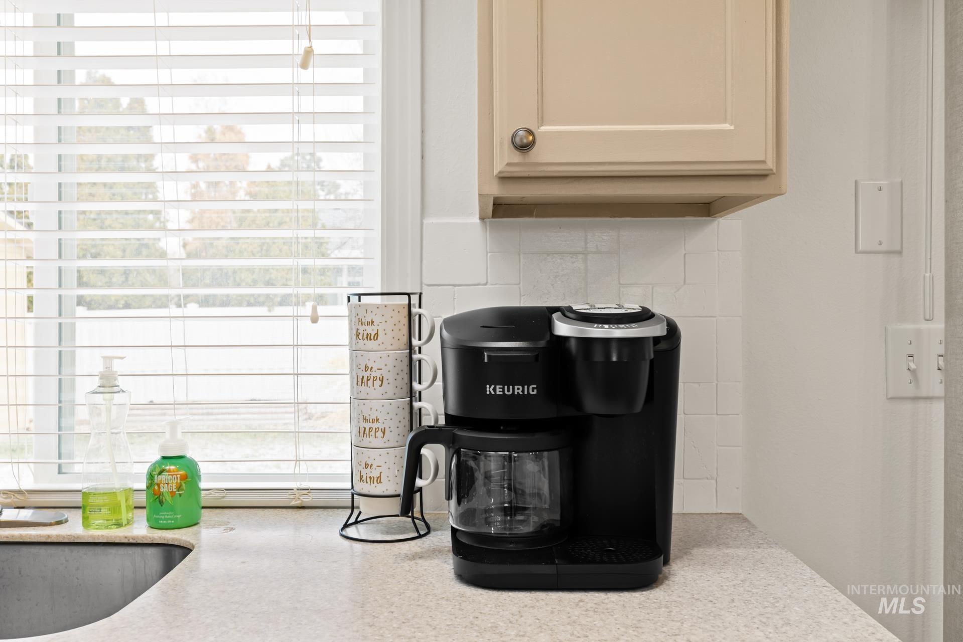 Kitchen view of tasteful backsplash and cream cabinetry