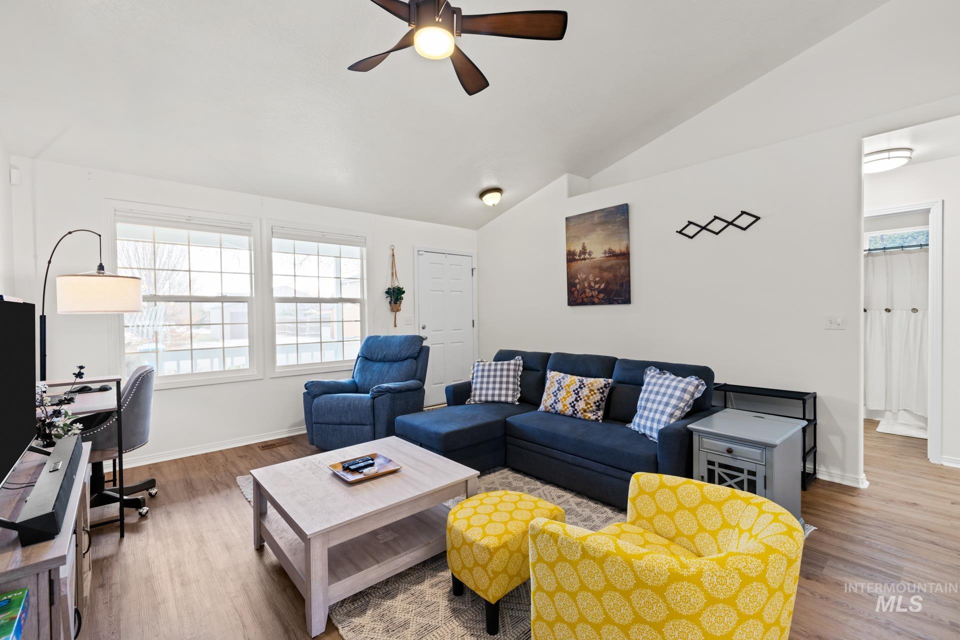 Living room featuring lofted ceiling, wood finished floors, ceiling fan, and a desk