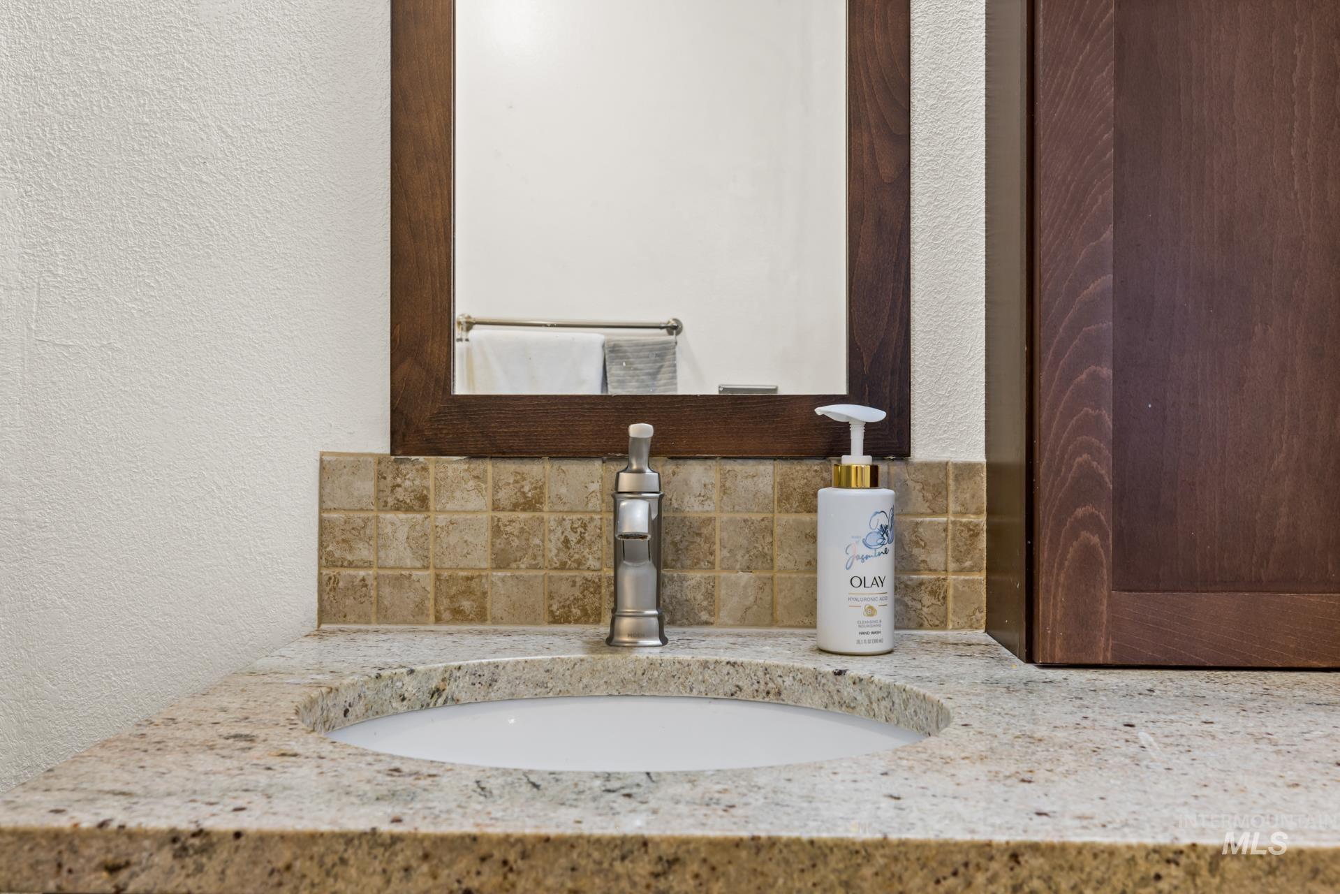Bathroom with a textured wall, decorative backsplash, and vanity