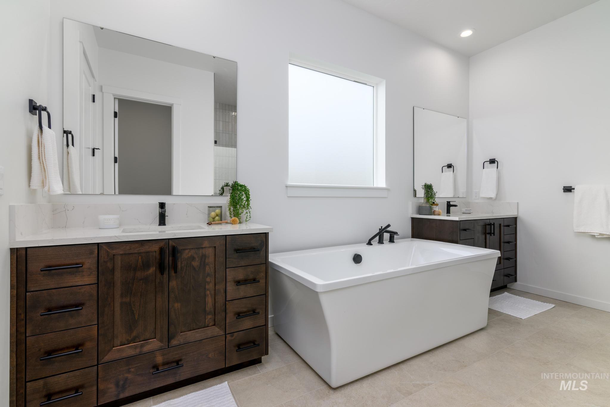 Bathroom with two vanities, a soaking tub, and recessed lighting