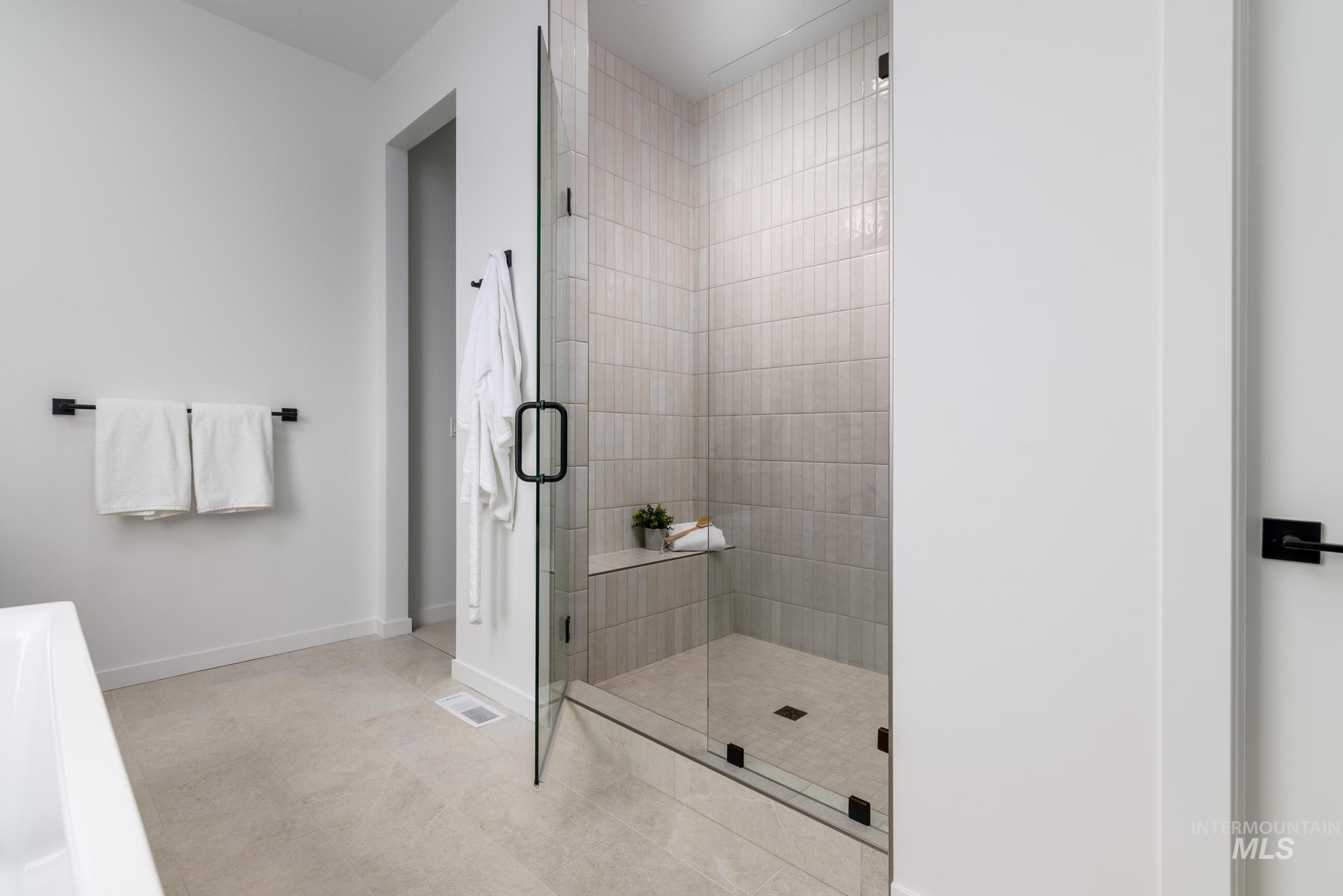 Full bath featuring a shower stall and light tile patterned floors