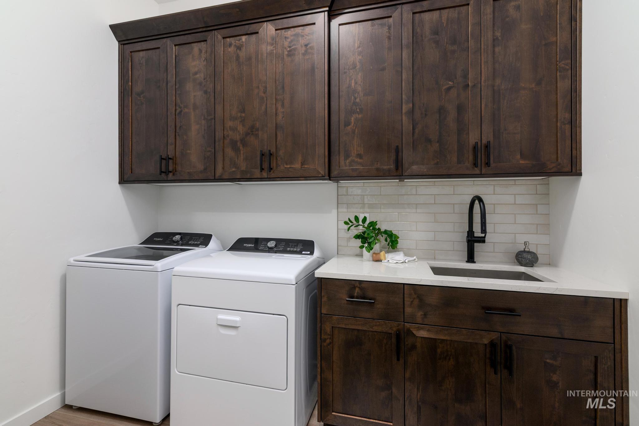 Washroom featuring washer and clothes dryer, cabinet space, and light wood-style floors