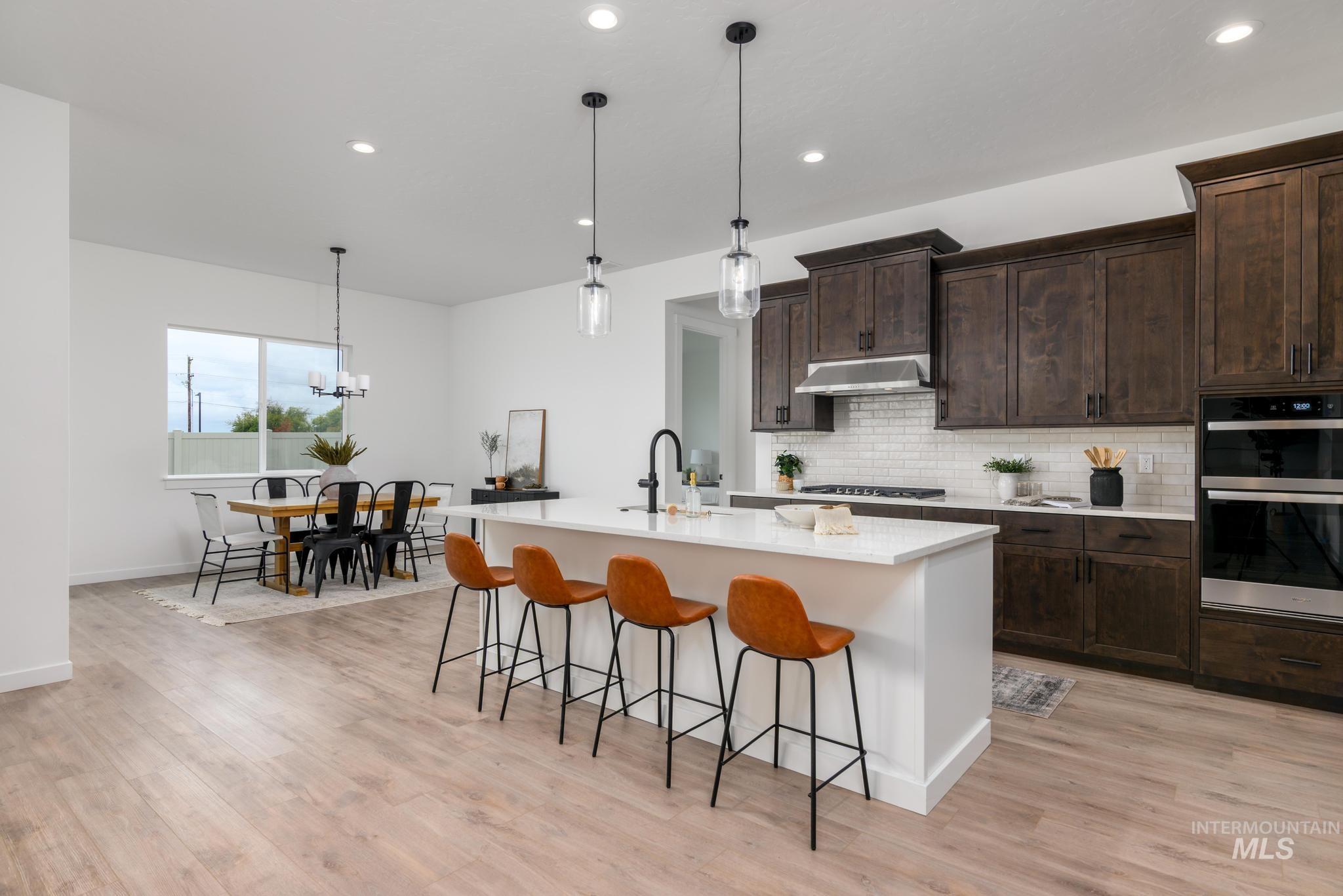 Kitchen with backsplash, hanging light fixtures, dark brown cabinetry, a breakfast bar, and recessed lighting
