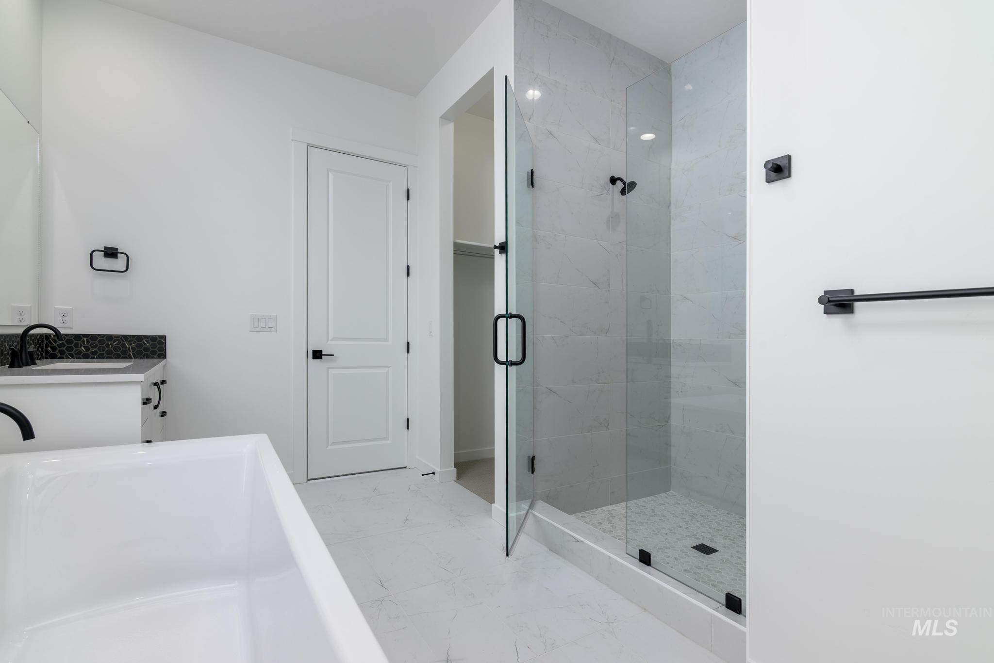 Bathroom with a soaking tub, vanity, light marble finish flooring, and a shower stall