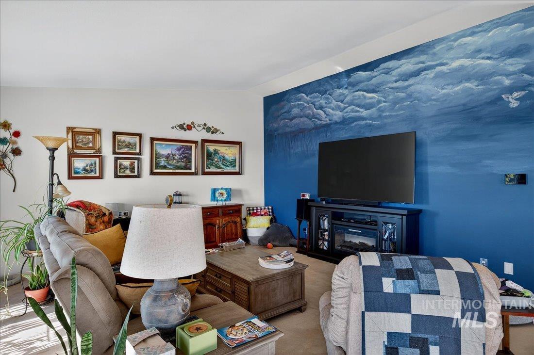 Carpeted living area featuring a glass covered fireplace