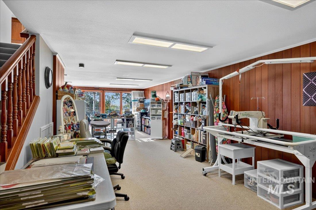 Office space with wood walls, light colored carpet, and a textured ceiling