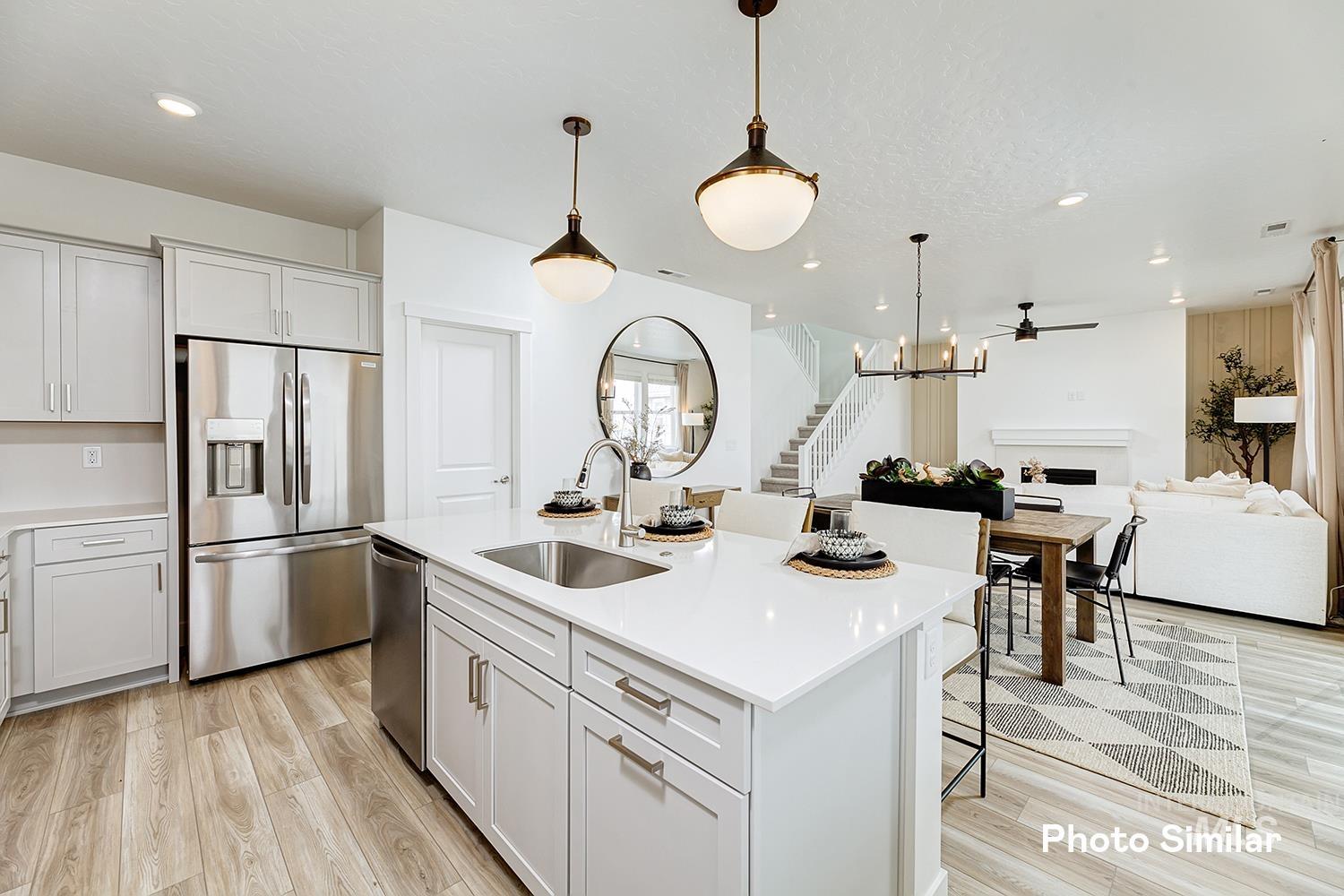 Kitchen with a fireplace, appliances with stainless steel finishes, a kitchen bar, decorative light fixtures, and light wood-type flooring