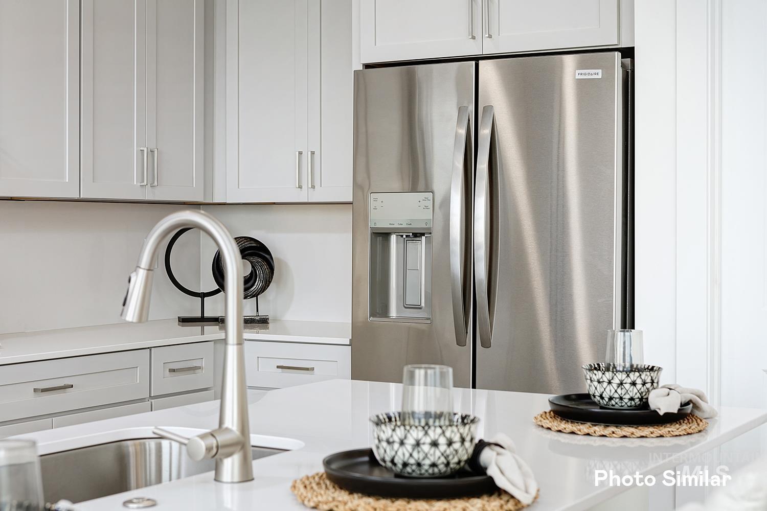 Kitchen with stainless steel refrigerator with ice dispenser, white cabinetry, and light stone counters