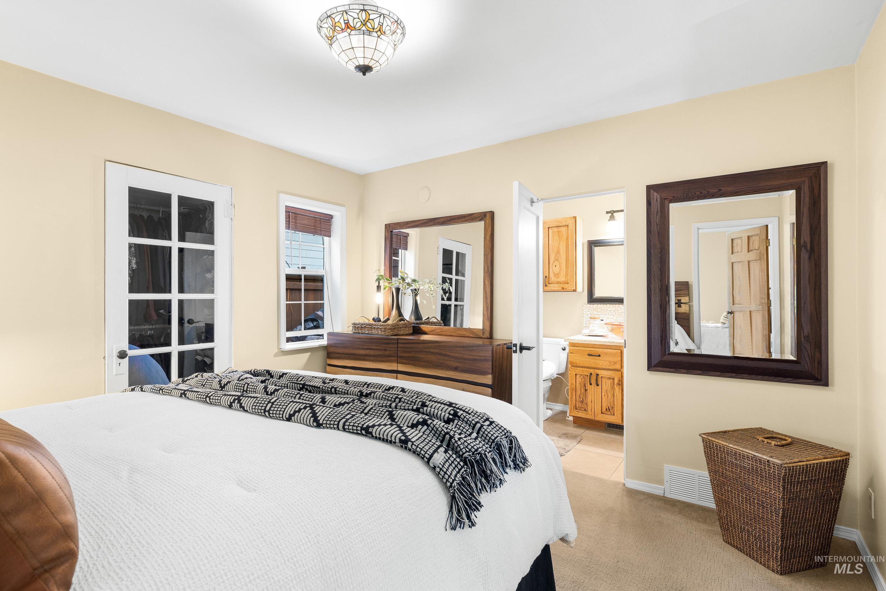 Bedroom with light carpet and ensuite bath