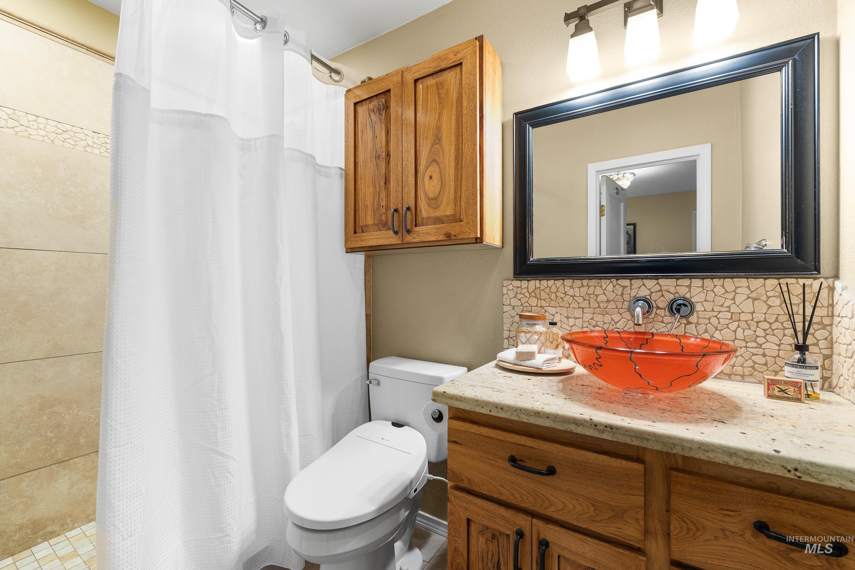 Full bathroom with decorative backsplash, a stall shower, and vanity