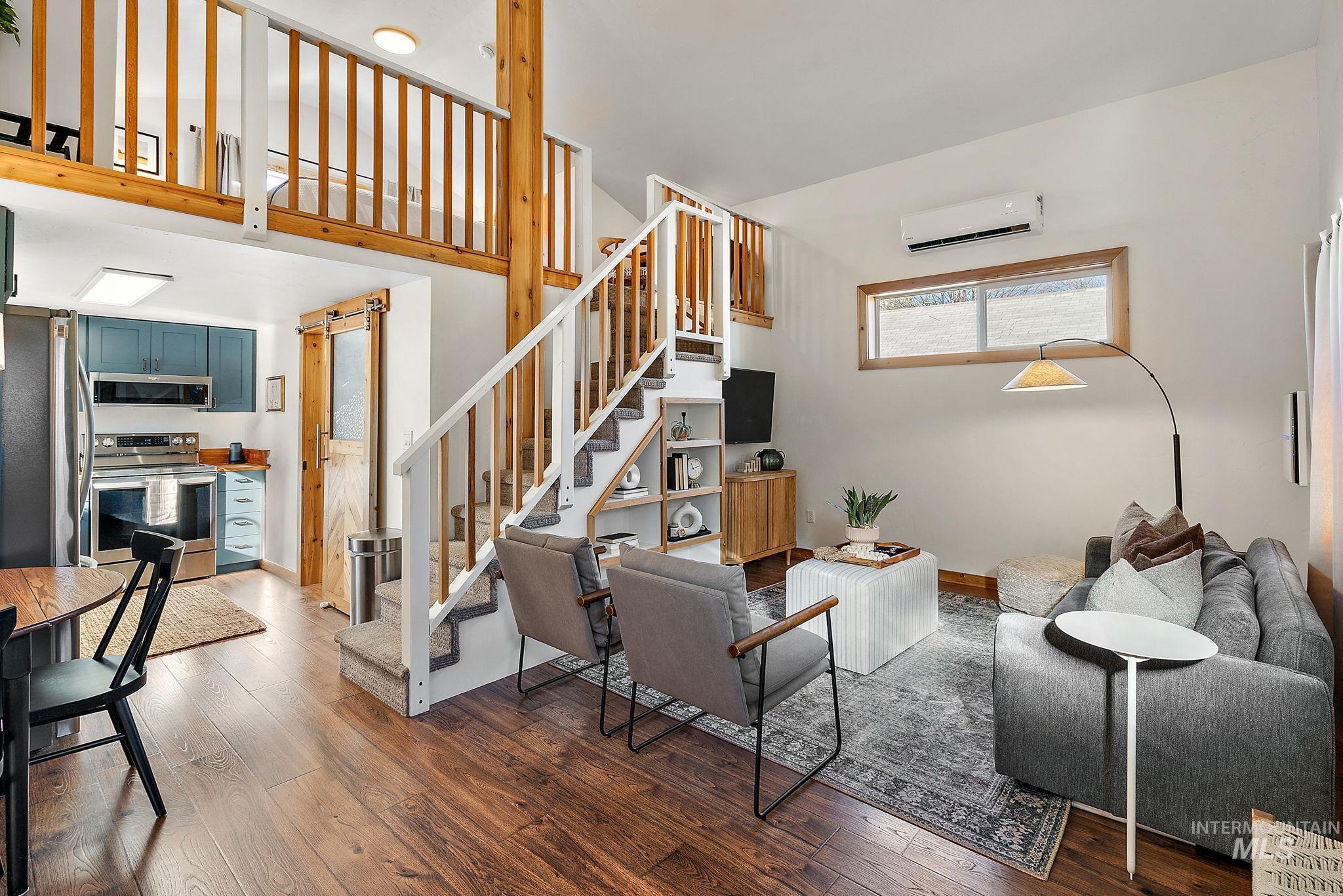 Living room featuring hardwood / wood-style flooring, an AC wall unit, and stairway